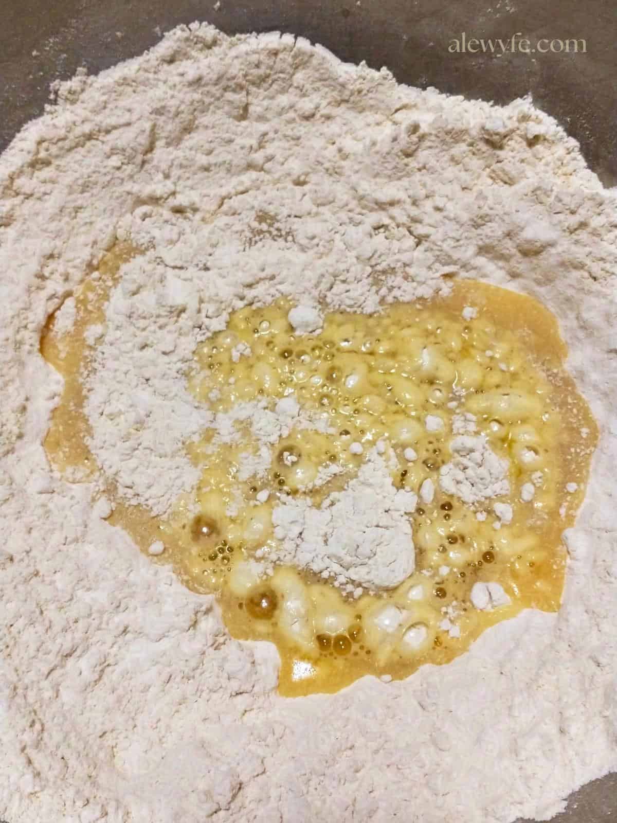 a bowl of flour with beaten egg before mixing pasta dough.