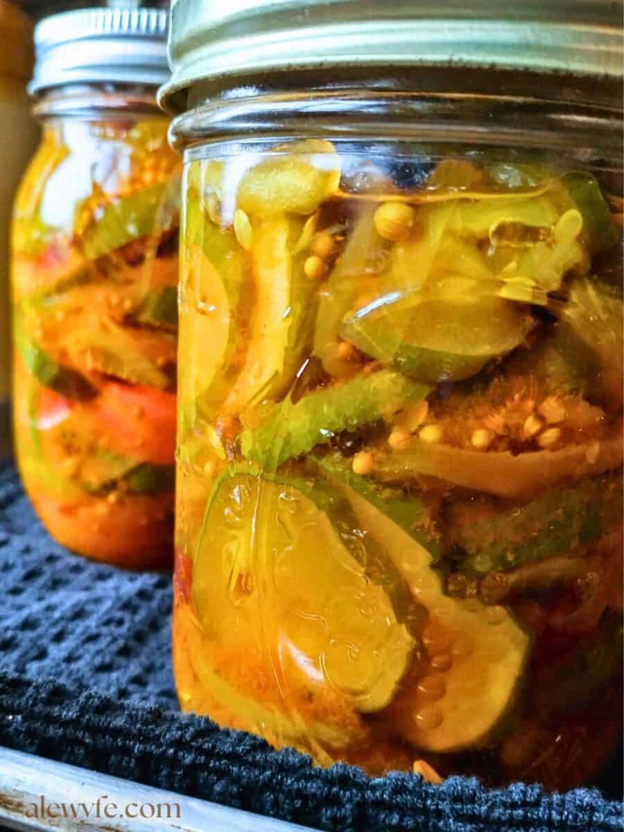 side view of two mason jars of freshly canned bread and butter pickles.