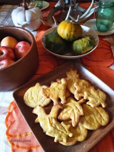 an autumn cornucopia with wooden bowls of apples, gourds, antlers, and pumpkin spice sugar cookies shaped like leaves & pumpkins.