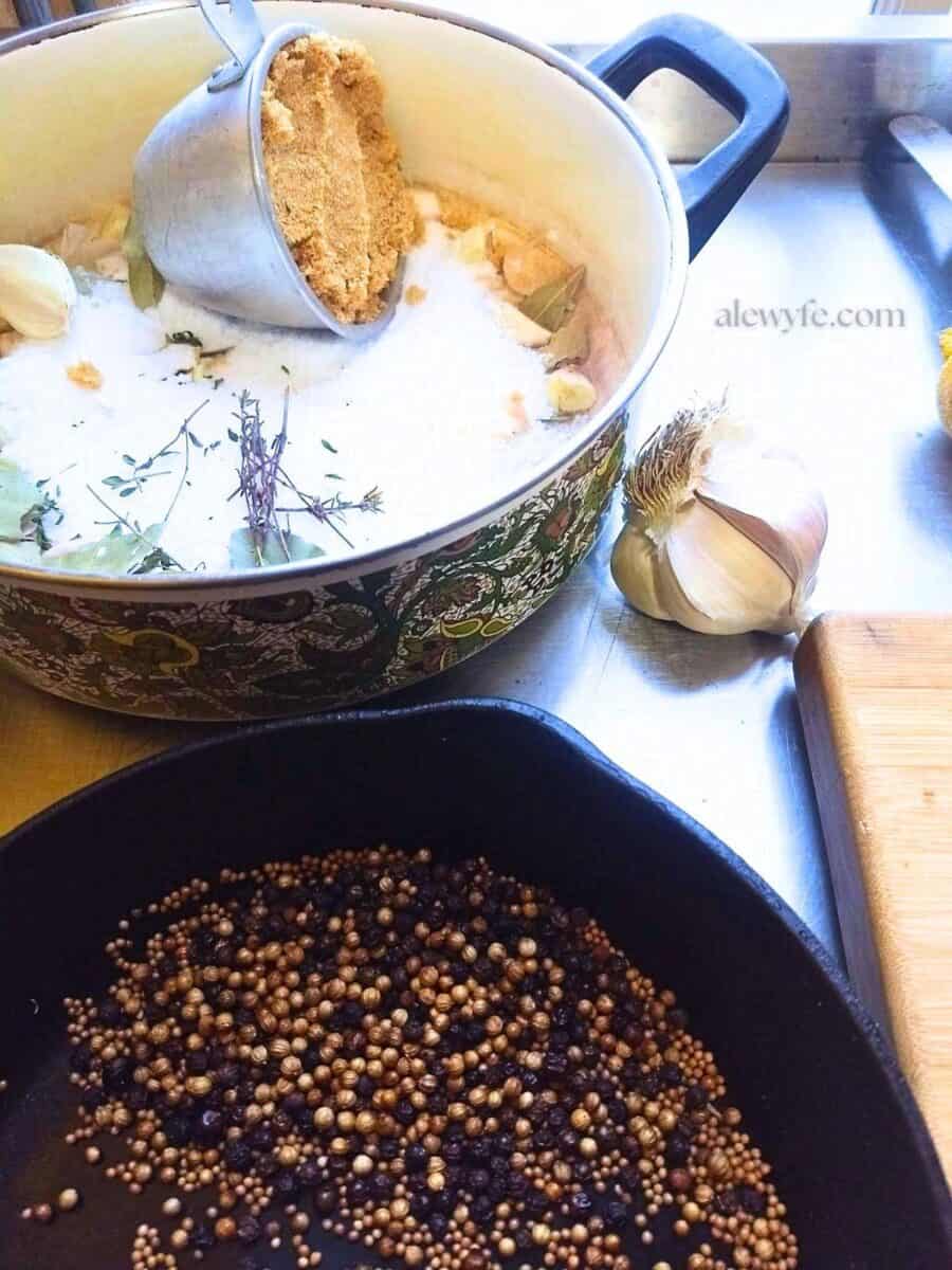 a pot with salt, sugar, garlic and herbs next to a cast iron pan with toasted spices. 