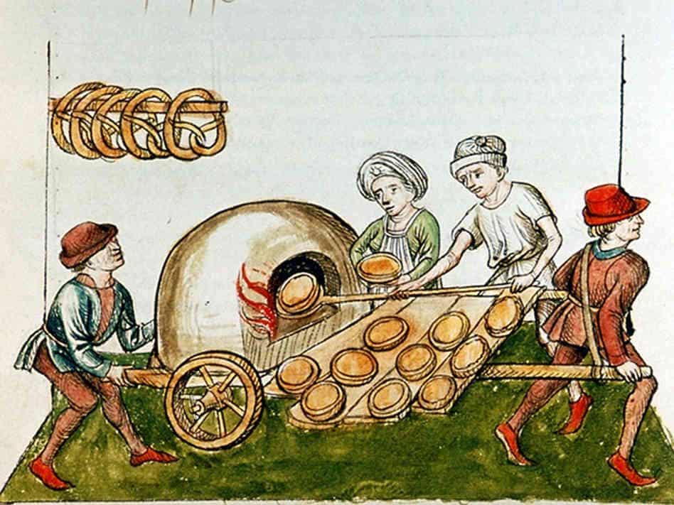 a group of medieval bakers baking pies in a portable oven on a cart. large pretzels hang on a hook in the background.
