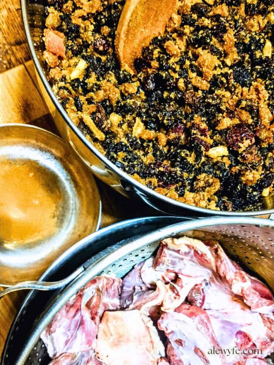 three stainless bowls, one filled with dried fruit, brown sugar, and citrus, one with meat to be ground, and spices.