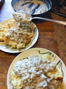 spooning sausage gravy over plates of split buttermilk cathead biscuits.