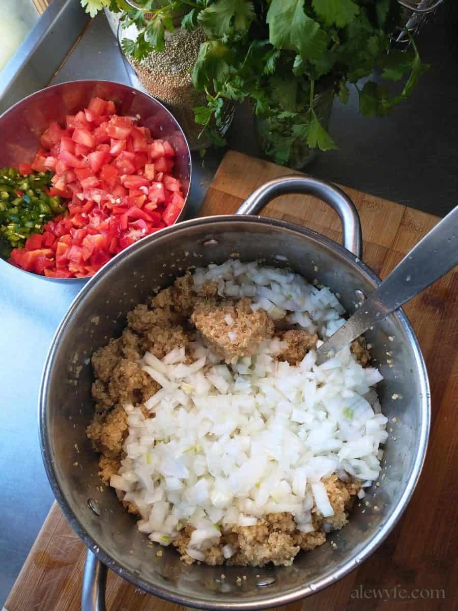 mixing sweet onions, diced peppers and tomatoes, fresh cilantro, and cooked quinoa to make a salad.