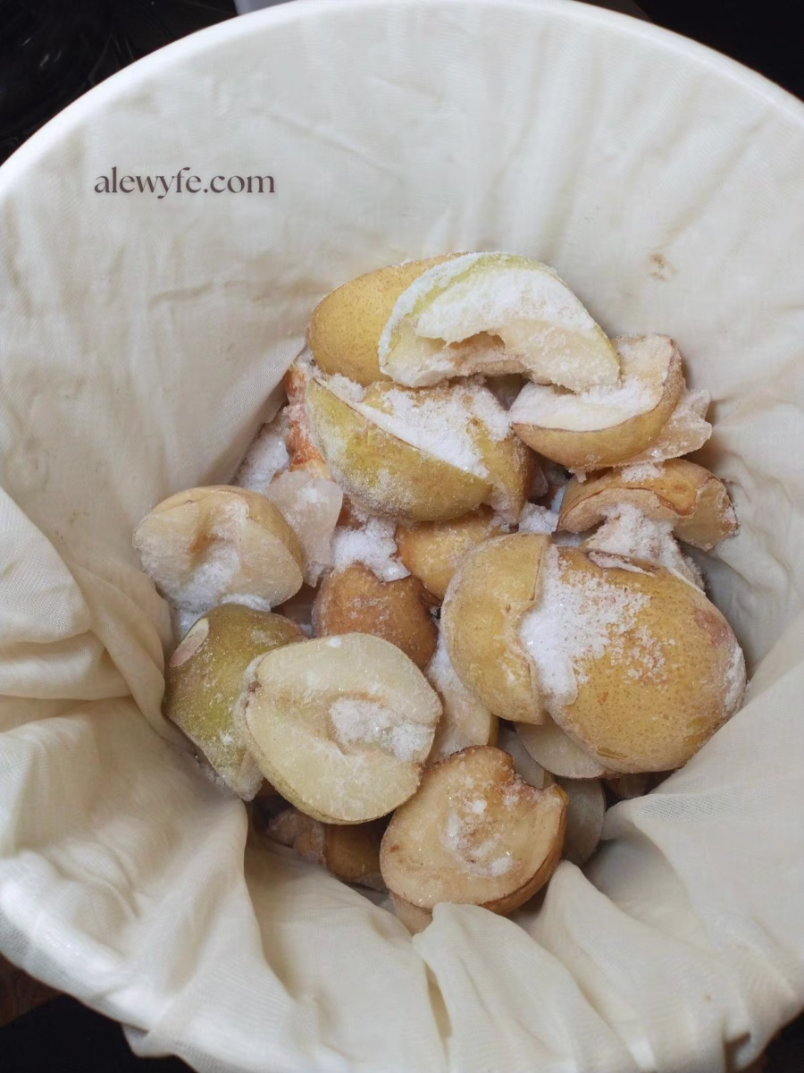halved frozen pears in a bucket lined with a mesh brewing bag.