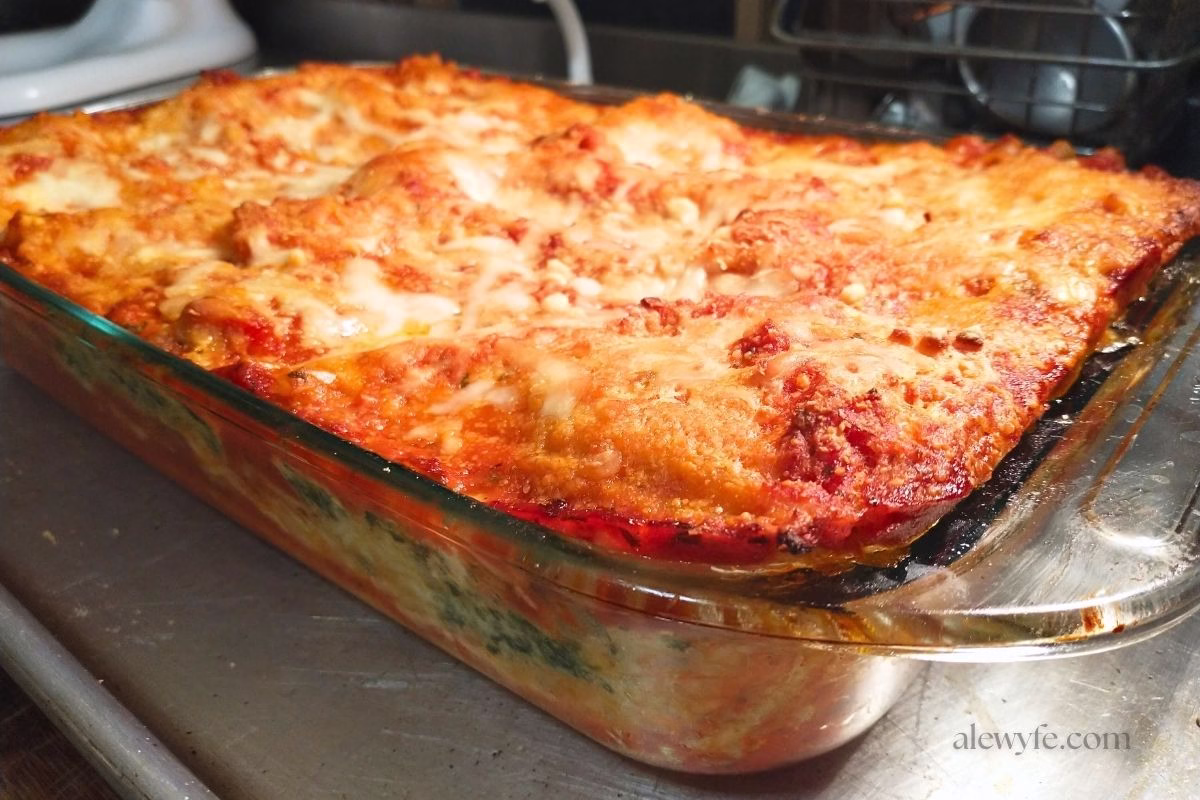 a baked dish of spinach lasagna cooling on a counter.