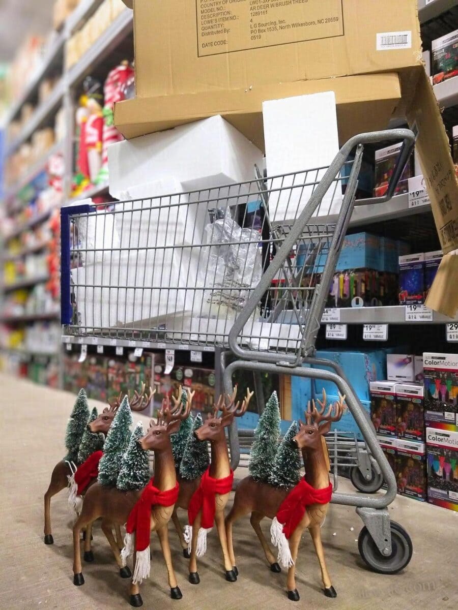 four plastic reindeer, wearing red scarves with green trees somehow sprouting out of their backs, sit in front of a shopping cart. It is overflowing with styrofoam blocks, plastic bags, and has a giant cardboard box on top the same size as the cart. This is the packing waste from these four objects.