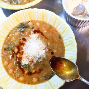 a bowl of chickpea and swiss chard stew, topped with garlic-infused paprika oil and grated Parmesan cheese.