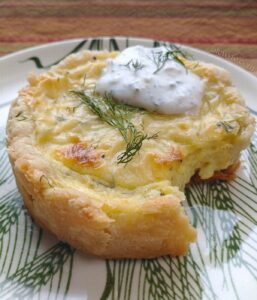 a plated potato goat cheese tart with horseradish dill crema and fresh dill garnish.