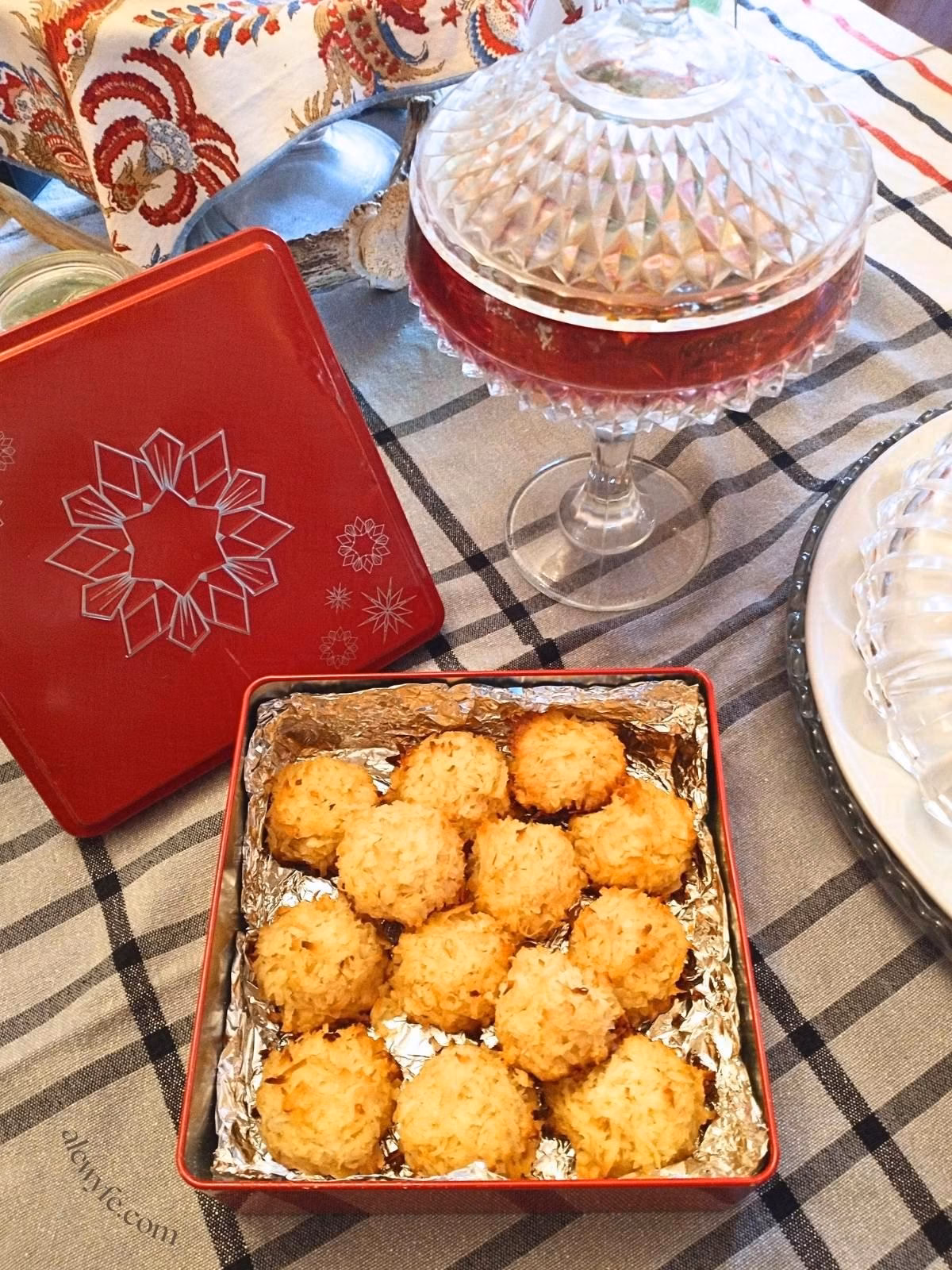 a table set with various dishes, and a red and silver tin of toasted coconut macaroons.