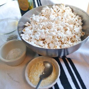 a bowl of popcorn, surrounded by small ramekins of Parmesan cheese, flaky sea salt, black pepper, and a bottle of black truffle oil.