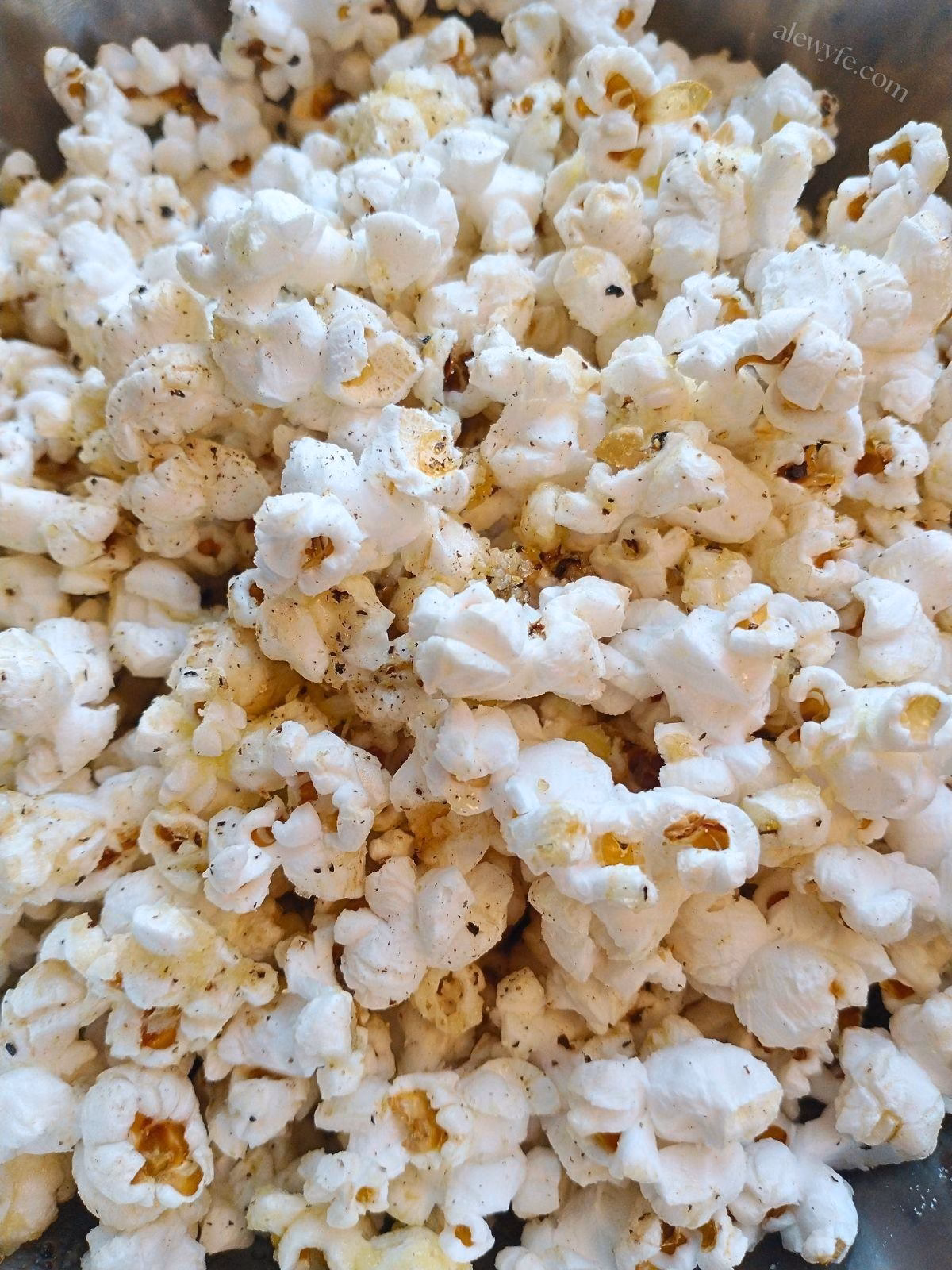 close-up photo of buttered black pepper popcorn with truffle oil and cheese.