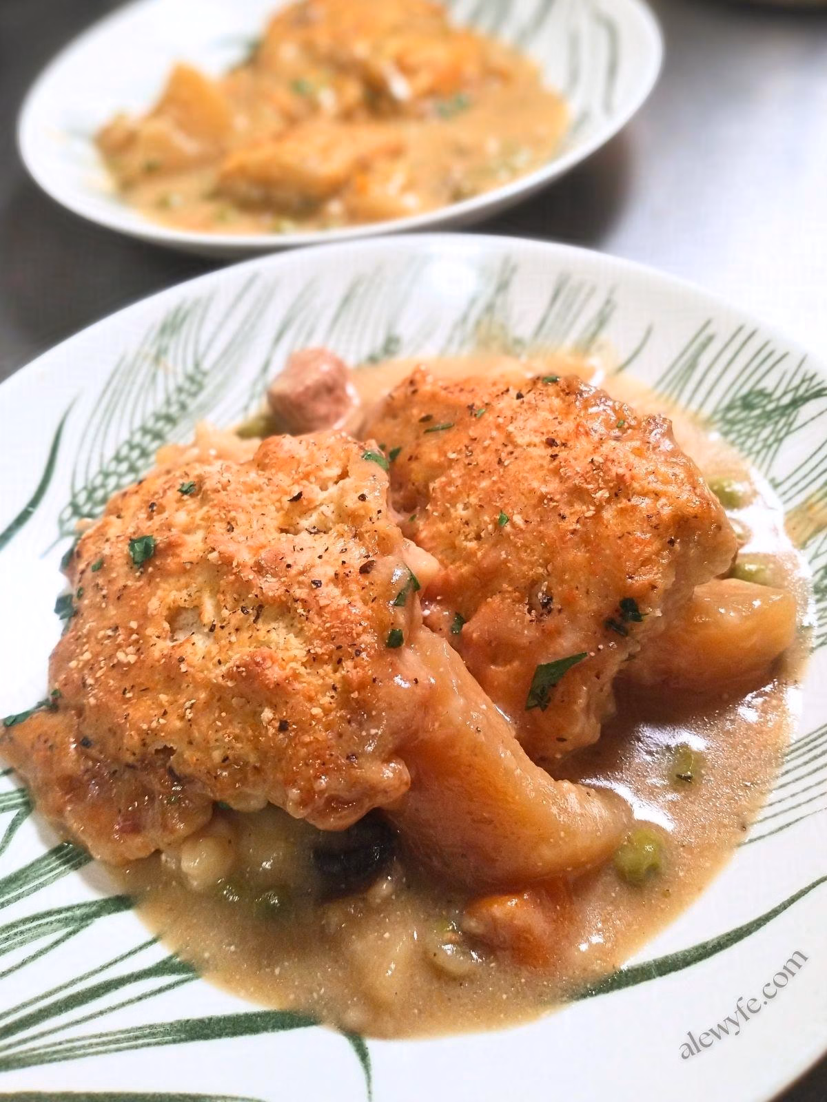 two bowls of chicken pot pie with herb & Parmesan drop biscuit topping.