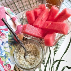a glass bowl of watermelon "fries" and a jar of homemade lime finishing salt.