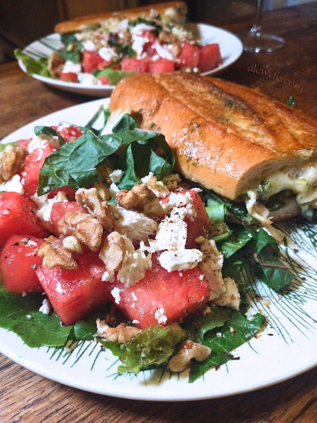 Plated watermelon, feta, and walnut salads with cheesy chicken pesto panini sandwiches.