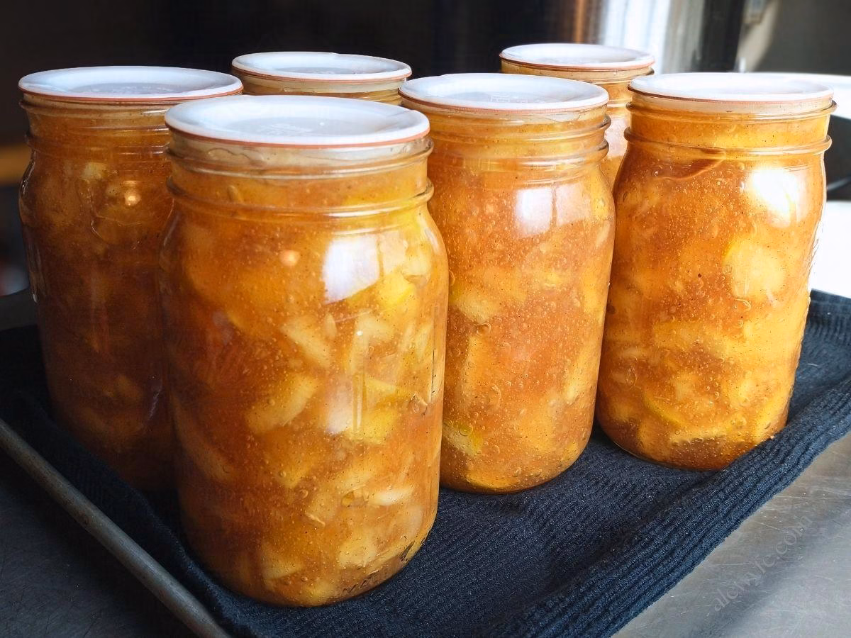 a tray of cooled, freshly canned apple pie filling in quart jars.