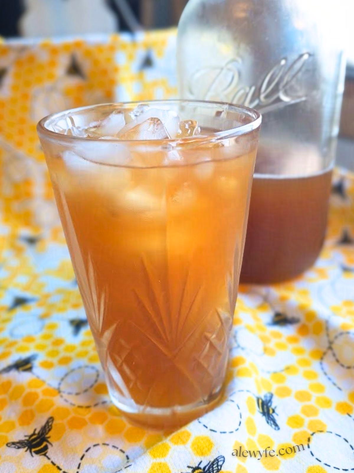 side view of a cut crystal glass of ginger peach ice tea.