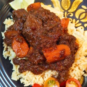 close-up plate shot of braised ancho coffee venison with carrots and peppers on a bed of rice pilaf.