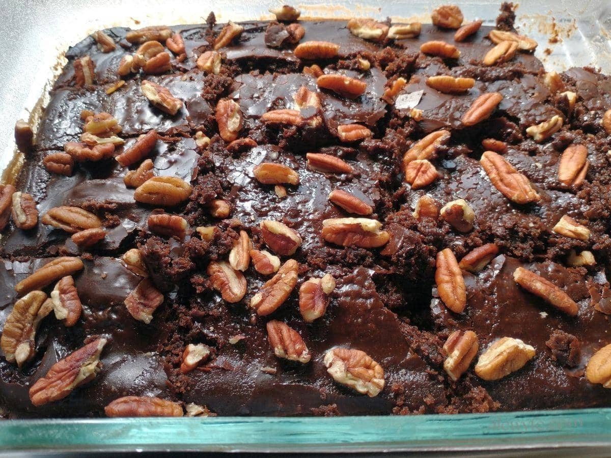 a sliced chocolate buttermilk sheet cake topped with boiled mocha icing and chopped pecans.
