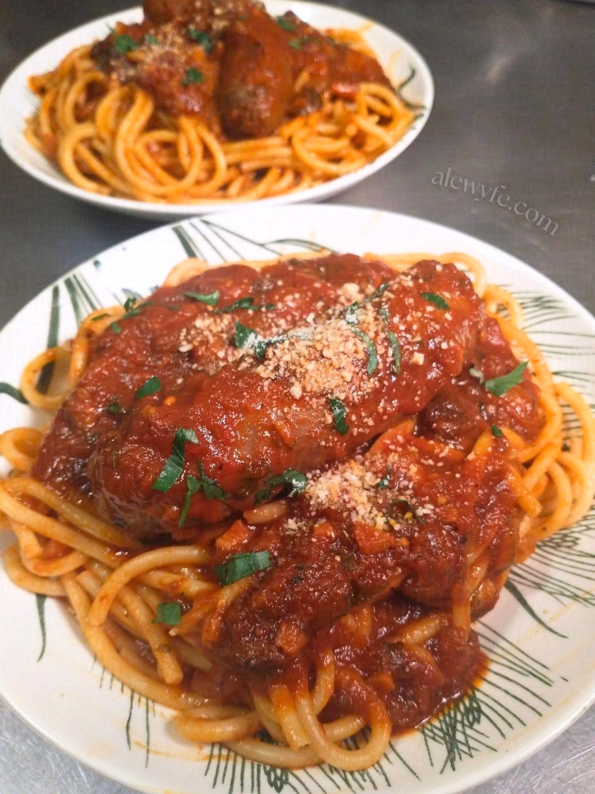 two plates of spaghetti with red sauce and venison italian sausages.